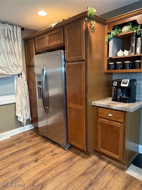 kitchen featuring light wood-type flooring, light countertops, backsplash, and stainless steel fridge with ice dispenser