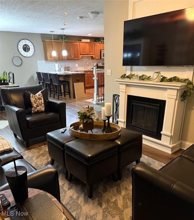 living room featuring a textured ceiling, a fireplace, and wood finished floors