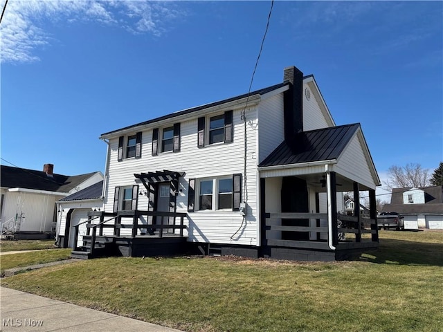 view of front facade with a chimney, covered porch, a front yard, a standing seam roof, and metal roof