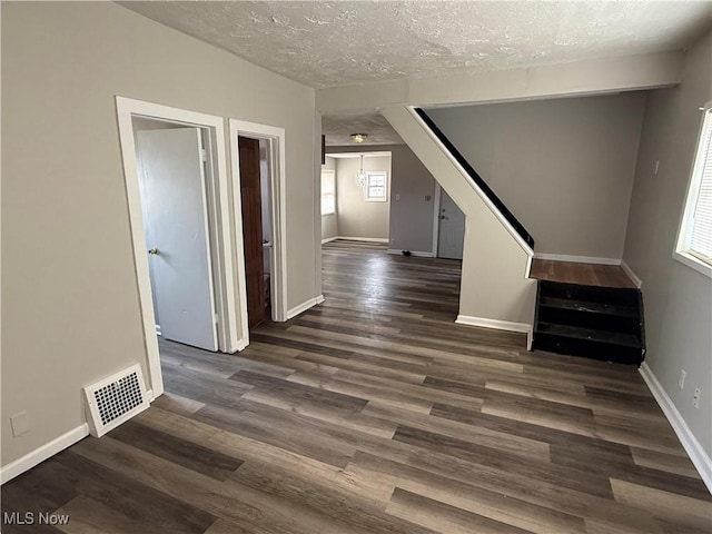 interior space featuring baseboards, a textured ceiling, visible vents, and wood finished floors