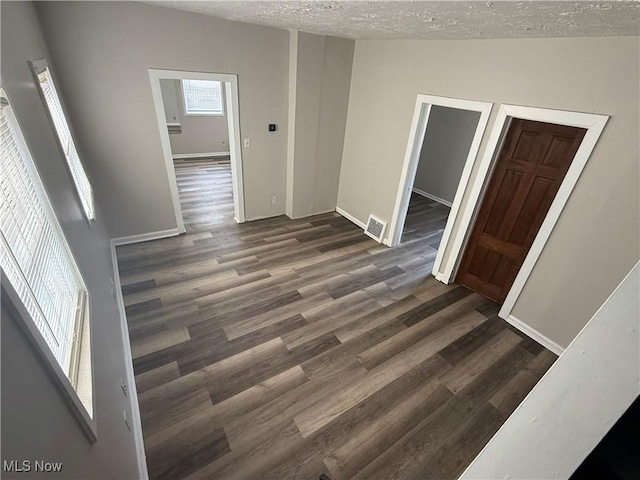 interior space featuring visible vents, a textured ceiling, baseboards, and wood finished floors