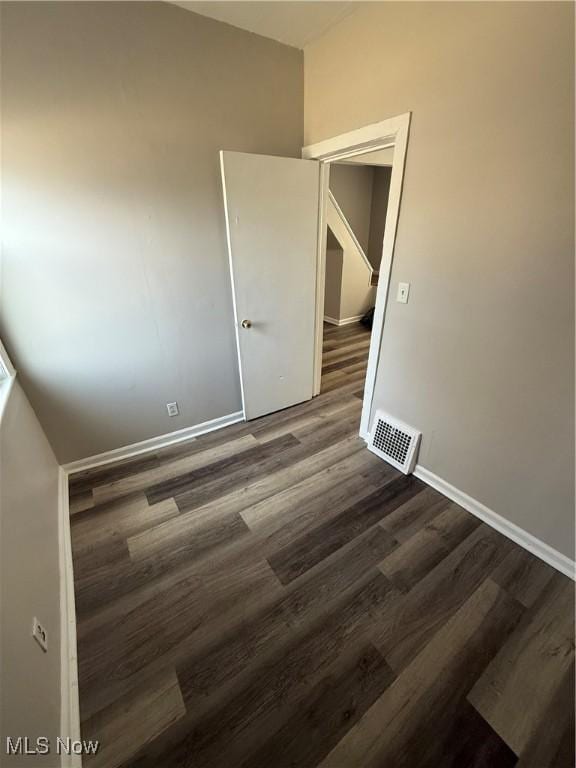 spare room featuring wood finished floors, visible vents, and baseboards