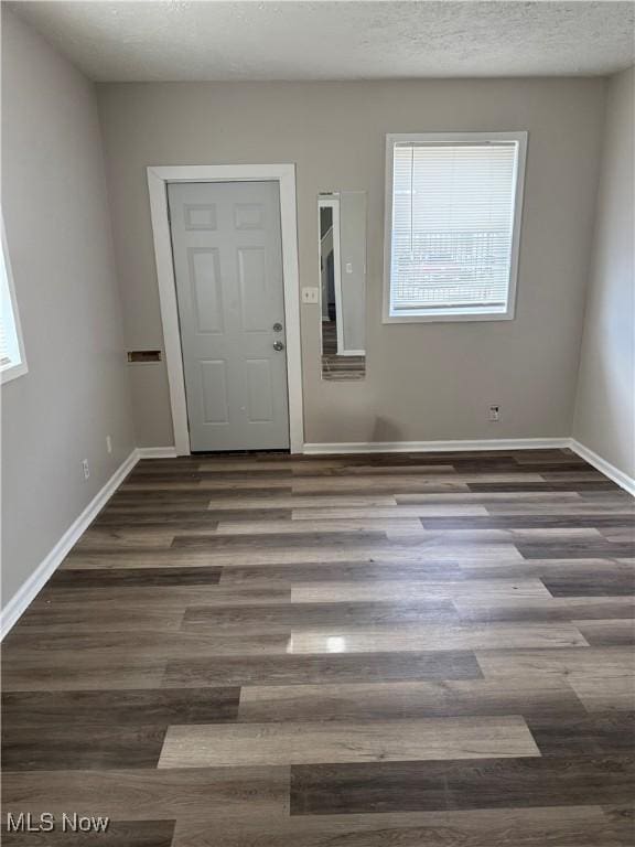 interior space featuring a textured ceiling, baseboards, and wood finished floors