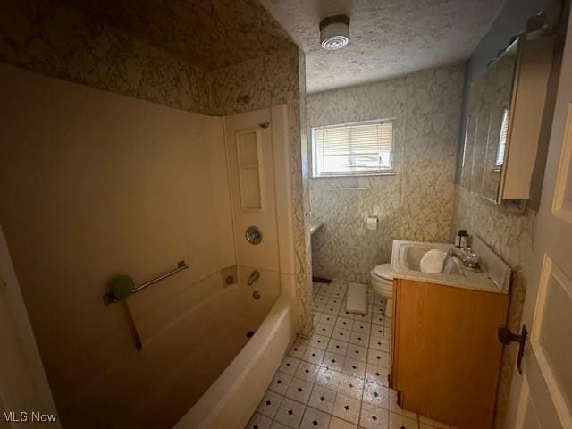 bathroom featuring a textured ceiling, toilet, vanity, shower / washtub combination, and tile patterned floors