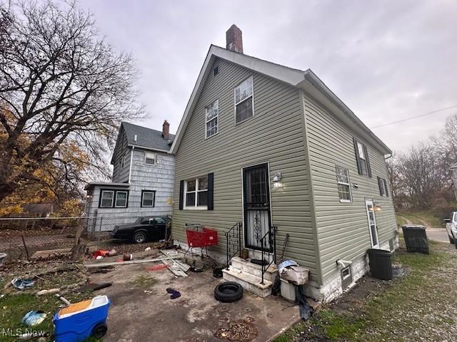 rear view of property featuring entry steps and fence