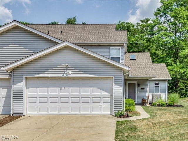 view of front of property with a front yard, roof with shingles, driveway, and an attached garage