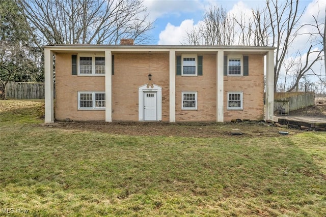 exterior space featuring a front yard, brick siding, fence, and a chimney