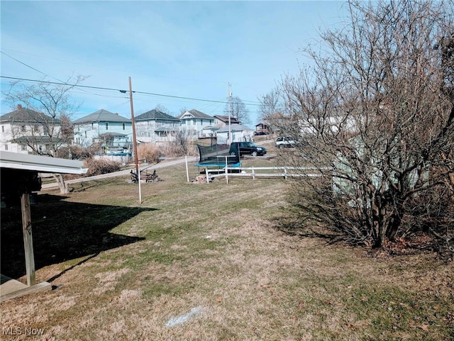 view of yard with a trampoline, a residential view, and fence