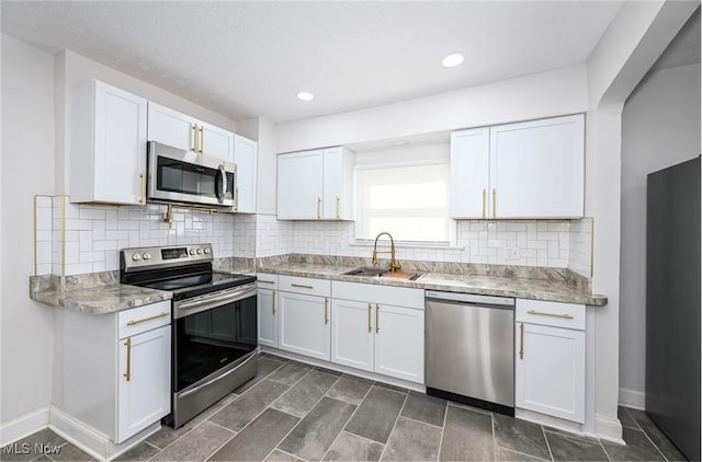 kitchen featuring a sink, baseboards, white cabinets, appliances with stainless steel finishes, and backsplash