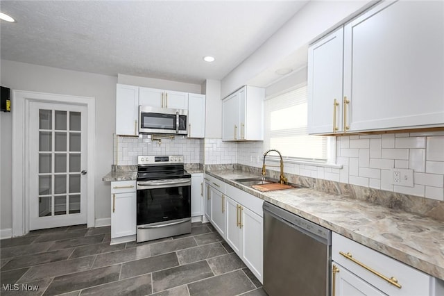 kitchen featuring stainless steel appliances, tasteful backsplash, a sink, and white cabinets