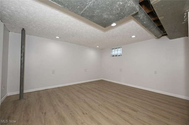 basement with a textured ceiling, baseboards, wood finished floors, and recessed lighting