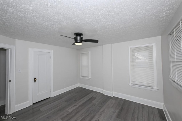 additional living space with a textured ceiling, dark wood finished floors, a ceiling fan, and baseboards