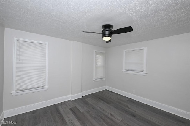 empty room featuring a textured ceiling, dark wood-type flooring, a ceiling fan, and baseboards