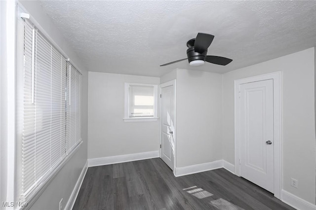 interior space with a textured ceiling, dark wood-type flooring, a ceiling fan, and baseboards