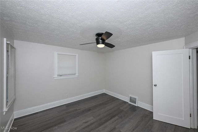 empty room featuring a ceiling fan, baseboards, visible vents, and dark wood-type flooring