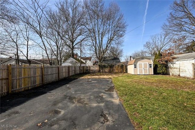 view of yard with a fenced backyard, an outdoor structure, and a storage unit