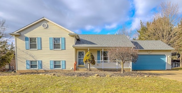 split level home with covered porch, a garage, concrete driveway, roof with shingles, and a front yard