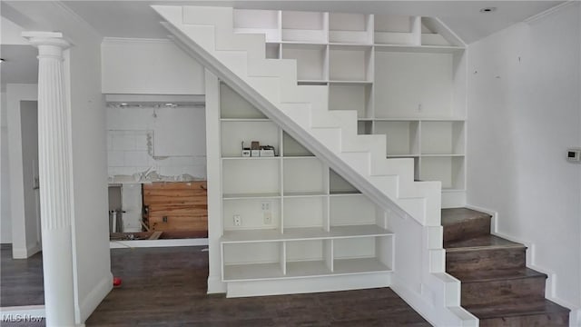 stairway with ornamental molding, wood finished floors, and decorative columns