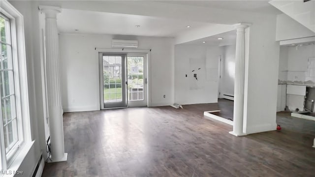 unfurnished living room with a wall unit AC, a baseboard radiator, recessed lighting, wood finished floors, and ornate columns