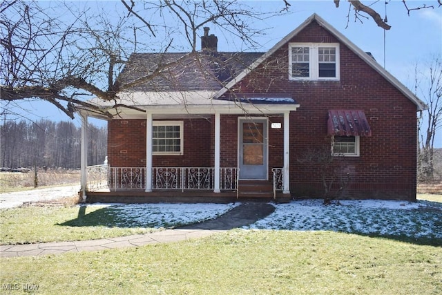 bungalow featuring covered porch, brick siding, a chimney, and a front lawn