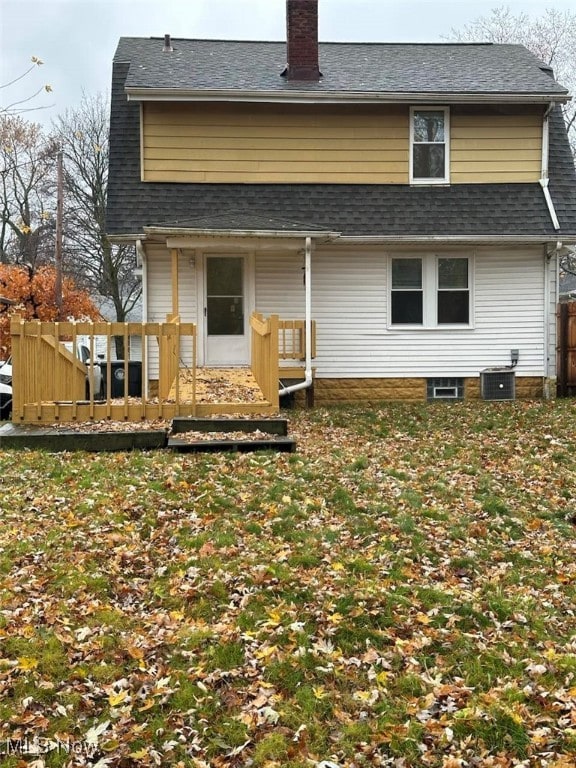 rear view of house with a deck, a shingled roof, a chimney, and cooling unit