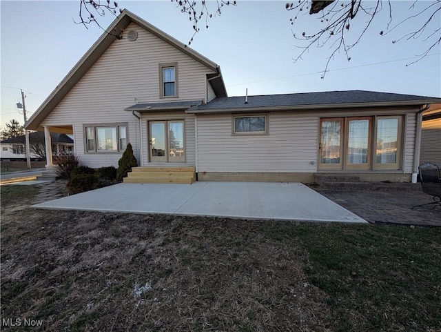 rear view of property with entry steps, a patio area, and a lawn