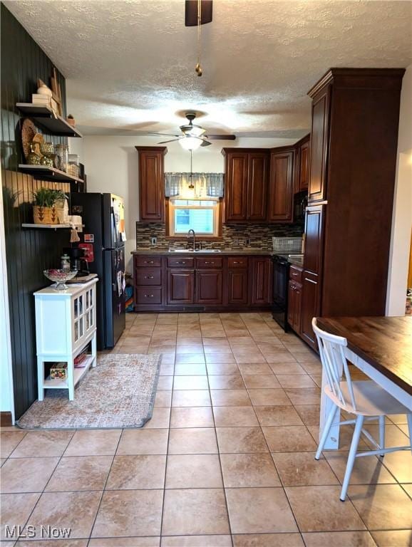 kitchen with tasteful backsplash, dark countertops, black appliances, a sink, and light tile patterned flooring