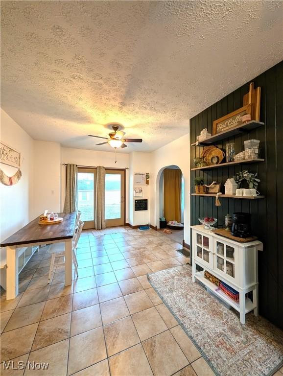 interior space with arched walkways, ceiling fan, a textured ceiling, and light tile patterned floors