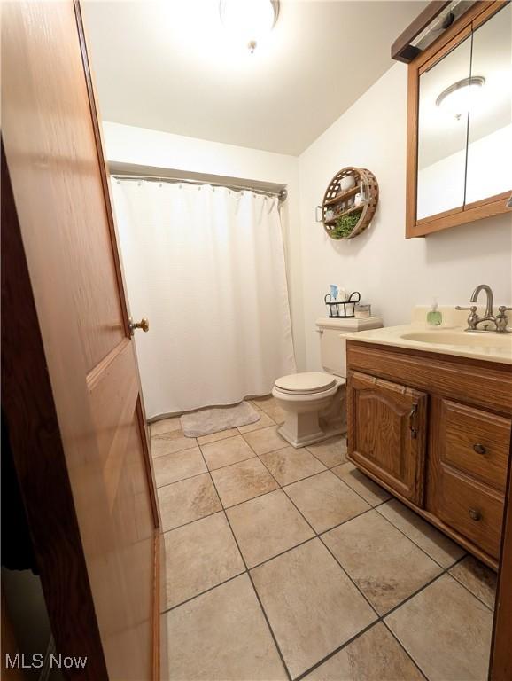 bathroom featuring tile patterned flooring, curtained shower, vanity, and toilet