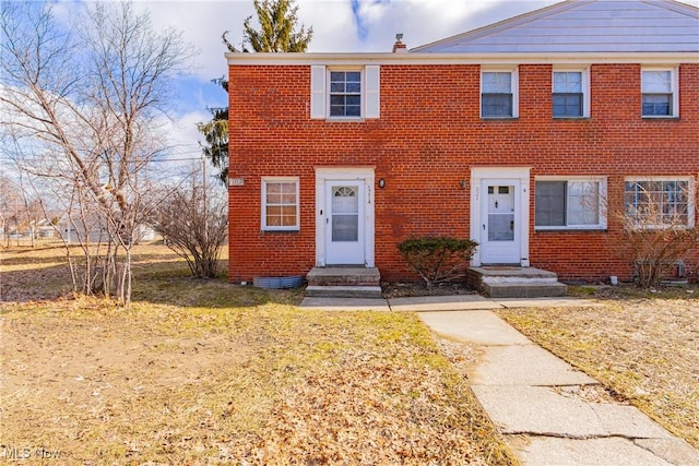 view of front of property with entry steps, brick siding, and a front yard