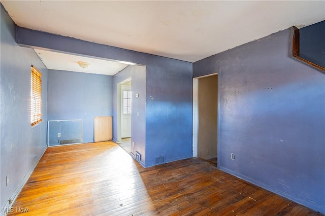 unfurnished room with wood-type flooring, visible vents, and a wealth of natural light