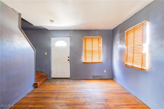 entrance foyer featuring wood-type flooring, visible vents, baseboards, and stairs