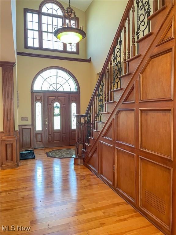 foyer entrance featuring stairway, a towering ceiling, and light wood-style flooring