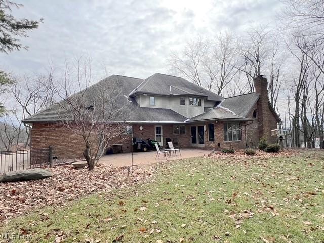 rear view of property featuring a yard, brick siding, a patio, and fence