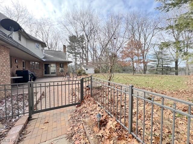 exterior space featuring a patio area, a chimney, fence, and brick siding