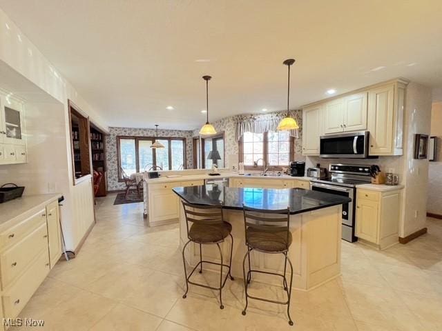 kitchen with stainless steel appliances, a sink, a peninsula, a kitchen bar, and wallpapered walls