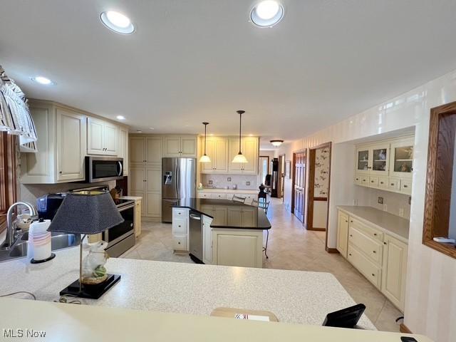 kitchen featuring stainless steel appliances, a kitchen island, a sink, and recessed lighting