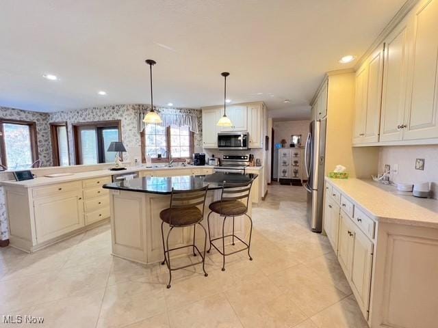 kitchen featuring appliances with stainless steel finishes, a kitchen island, a peninsula, a kitchen breakfast bar, and wallpapered walls