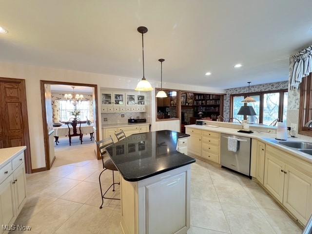 kitchen with a breakfast bar, a sink, stainless steel dishwasher, a center island, and glass insert cabinets