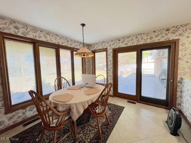 dining room featuring wallpapered walls, baseboards, visible vents, and light tile patterned flooring