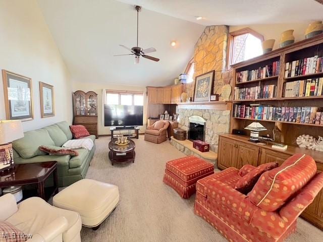 living room featuring plenty of natural light, light colored carpet, a ceiling fan, and a stone fireplace