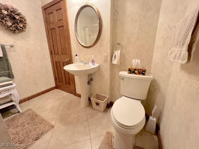 bathroom with toilet, baseboards, a sink, and tile patterned floors