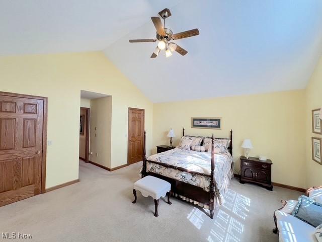 bedroom with light colored carpet, vaulted ceiling, baseboards, and ceiling fan