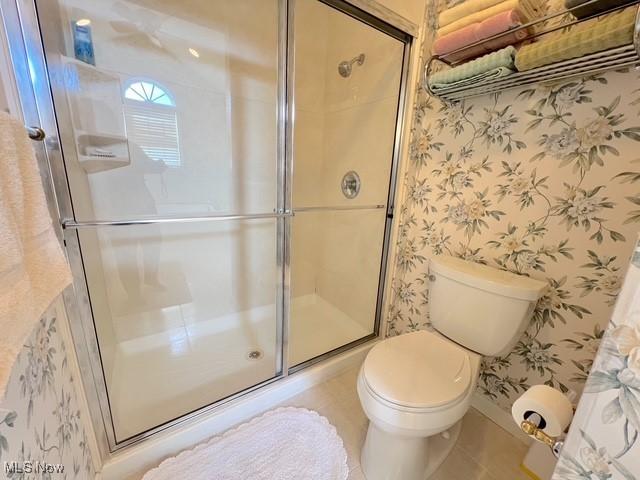 full bathroom with a shower stall, toilet, and wallpapered walls