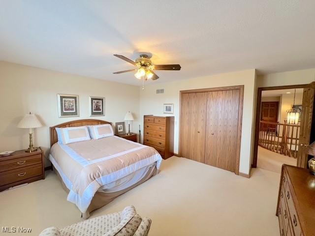 bedroom with a ceiling fan, a closet, light colored carpet, and visible vents