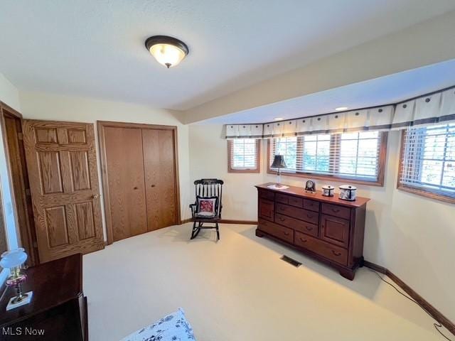 living area featuring light colored carpet and baseboards