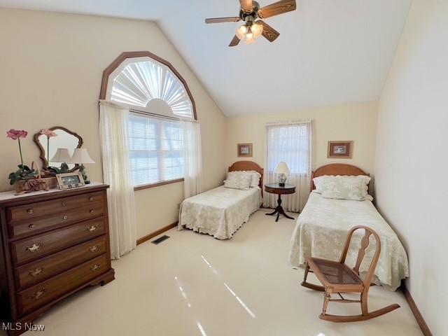 bedroom featuring lofted ceiling, light colored carpet, visible vents, ceiling fan, and baseboards