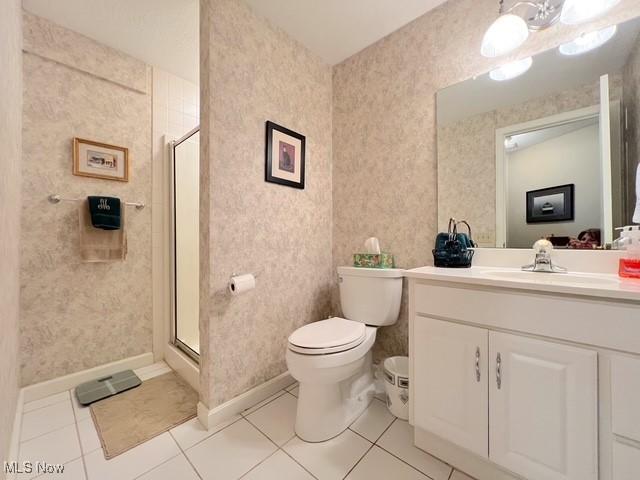 bathroom featuring toilet, vanity, a shower stall, tile patterned flooring, and wallpapered walls