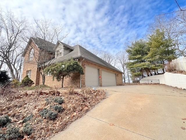 view of home's exterior featuring a garage, concrete driveway, and brick siding