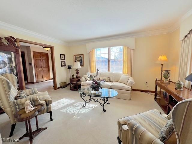 living area featuring crown molding, baseboards, and light colored carpet